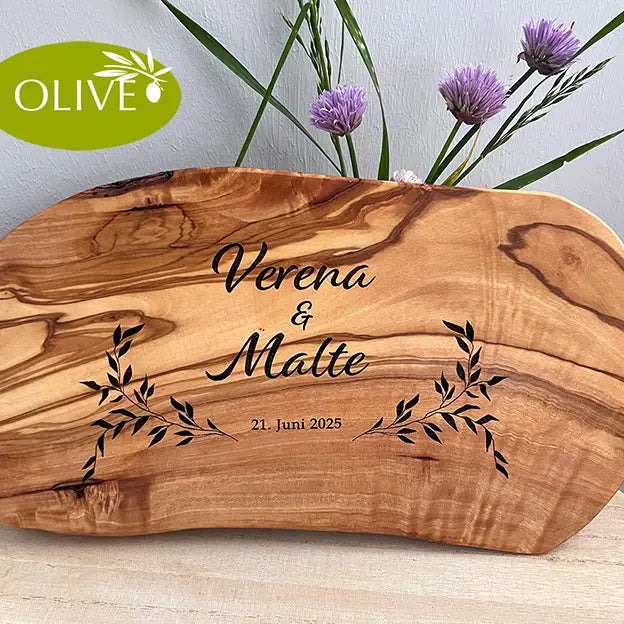 Glattes Schneidebrett aus Olivenholz mit Naturrand und personalisierter Gravur Motiv Reigen mit Namen und Datum in in modernen geschwungenen Schrift. Hier als Frühstücksbrett oder glattes Schneidebrett in verschiedenen Größen und Brettformen