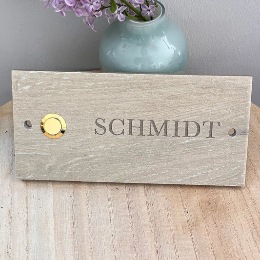 Personalisiertes Klingelschild (20x15 cm) aus beigefarbenen Keramik-Feinsteinzeug im Längsformat mit goldfarbenen Klingeltaster links. Name in Serifenschrift und Großbuchstaben. 2-Loch-Bohrlöcher für die Befestigung. Von Jeske Design
