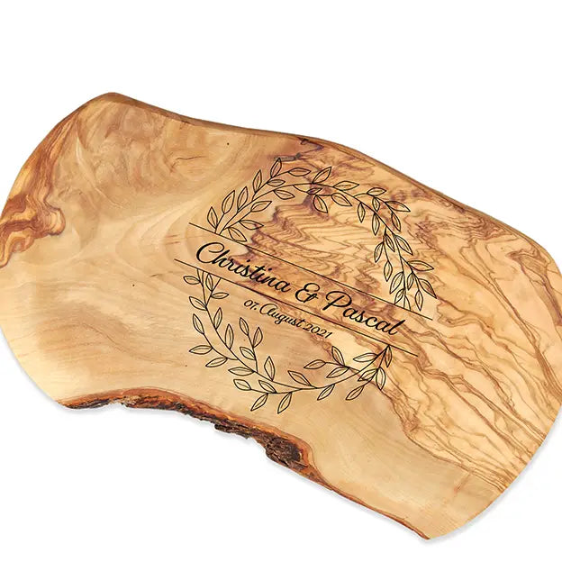 Glattes Schneidebrett aus Olivenholz mit Naturrand und personalisierter Gravur Motiv Blätterkranz mit Namen und Datum in in geschwungener Schrift. Hier als Frühstücksbrett oder glattes Schneidebrett in verschiedenen Größen und Brettformen