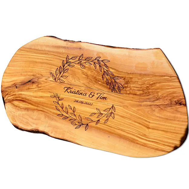 Glattes Schneidebrett aus Olivenholz mit Naturrand und personalisierter Gravur Motiv Blätterkranz mit Namen und Datum in in geschwungener Schrift. Hier als Frühstücksbrett oder glattes Schneidebrett in verschiedenen Größen und Brettformen
