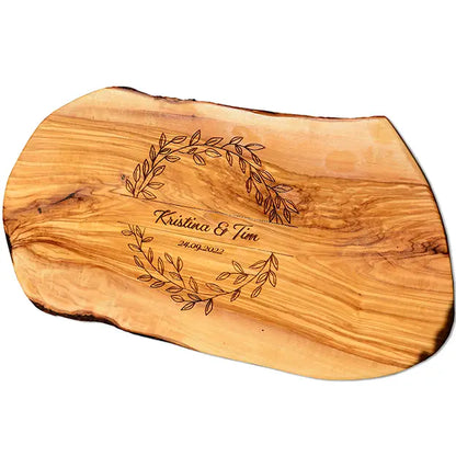 Glattes Schneidebrett aus Olivenholz mit Naturrand und personalisierter Gravur Motiv Blätterkranz mit Namen und Datum in in geschwungener Schrift. Hier als Frühstücksbrett oder glattes Schneidebrett in verschiedenen Größen und Brettformen