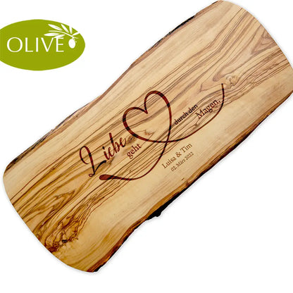 Motiv LIEBE GEHT DURCH DEN MAGEN auf ein Olivenholz glattes Schneidebrett graviert mit personalisierten Namen und Datum und einem geschwungenem Herz
