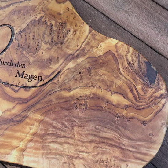 Motiv LIEBE GEHT DURCH DEN MAGEN auf ein Olivenholz glattes Schneidebrett graviert mit personalisierten Namen und Datum und einem geschwungenem Herz