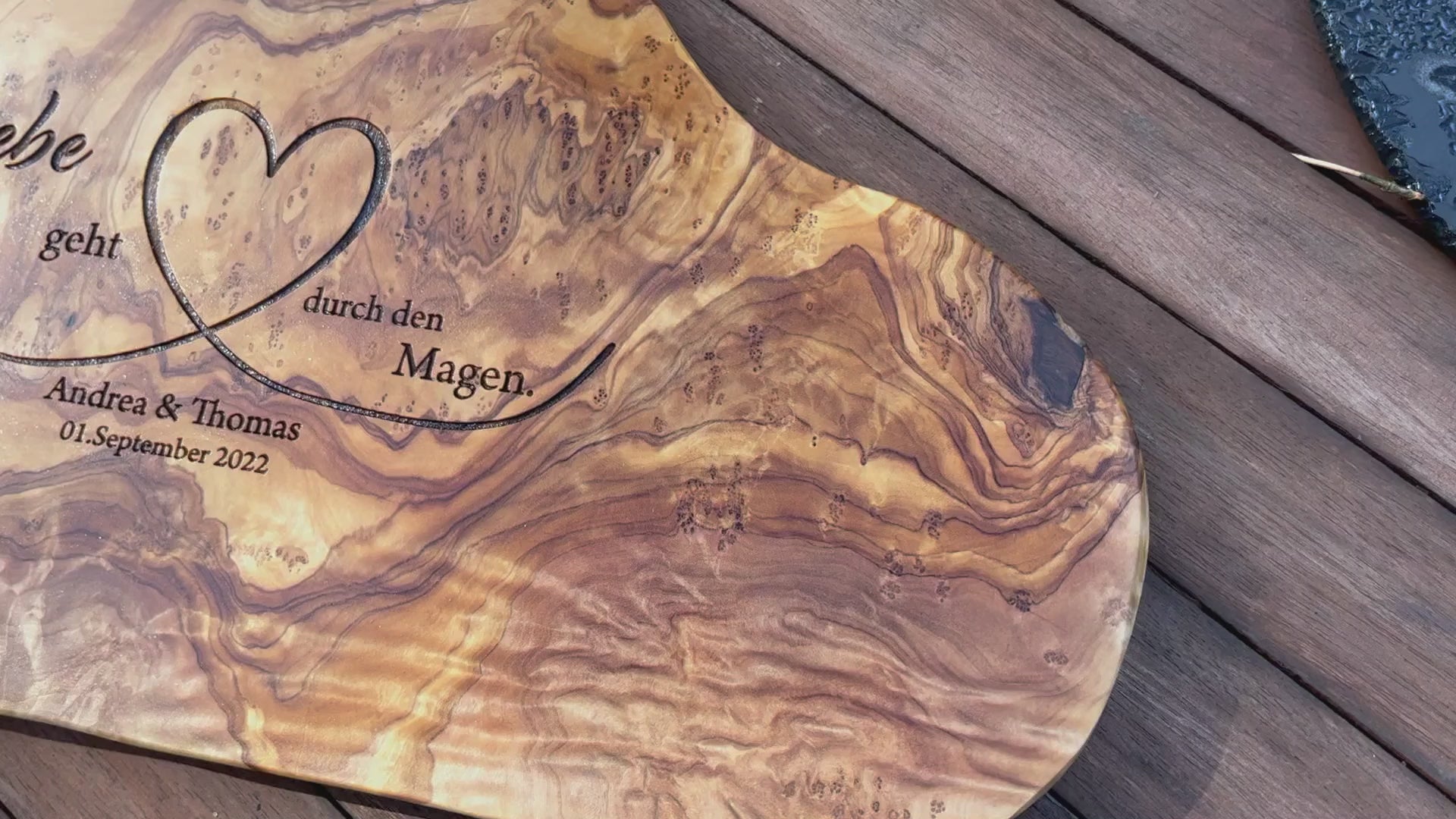 Motiv LIEBE GEHT DURCH DEN MAGEN auf ein Olivenholz glattes Schneidebrett graviert mit personalisierten Namen und Datum und einem geschwungenem Herz